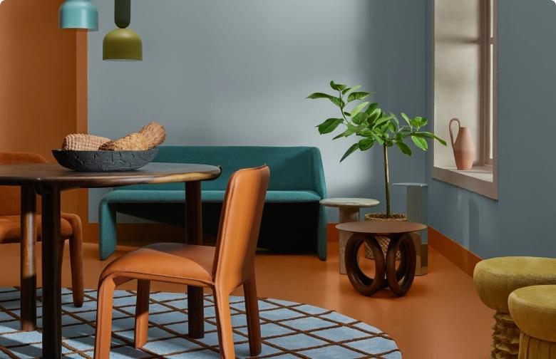 Uma sala com mesa, cadeiras, planta e uma parede pintada com a cor Conforto da Suvinil