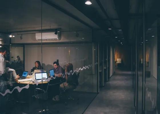 pessoas reunidas em um escritorio com pouca luminosidade Pessoas reunidas em um escritório com pouca luminosidade